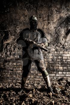 Post apocalyptic survivor, World War III soldier, global nuclear conflict partisan or stalker, in military cap and handmade body armor shooting with submachine gun wrapped in abandoned bunker or mine