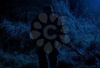 Army elite soldier, special forces fighter, infantry rifleman aiming service rifle with silencer in darkness, searching targets to shoot on stealth mission, spying and observing enemies positions