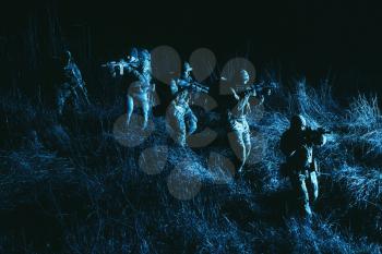 Commandos group, army special operations tactical group, military patrol team marching in field loaded with ammunition, sneaking in darkness, carefully and quiet moving in line during night mission