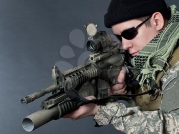 US soldier in black goggles aiming with his rifle