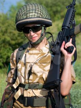 British girl soldier in desert uniform holding her rifle