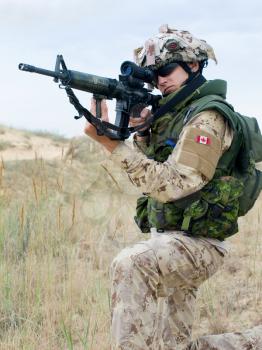 soldier in desert uniform aiming his rifle