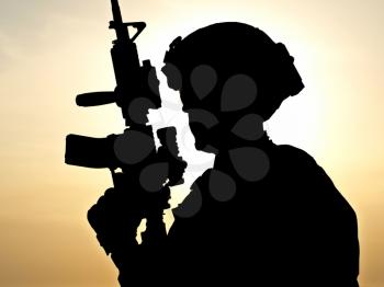 Silhouette of young soldier against the sun