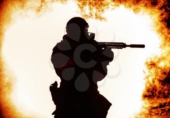 Black silhouette of soldier in the smoke moving in battle operation. Back light, cropped, toned and colorized