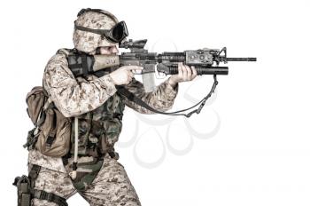 Studio shoot of yelling army soldier with machine gun, Marine Corps machine gunner in camo uniform with ammo belt on body armor, standing, screaming and firing from waist, isolated on white background