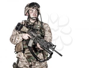 Studio shoot of marine infantry, commando soldier in full protective ammunition, standing with service rifle equipped grenade launcher and looking at camera, isolated on white background
