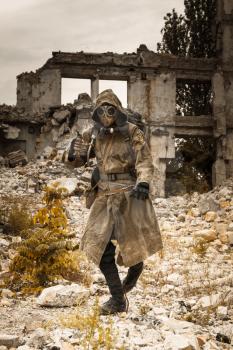 Post apocalypse. Sole survivor in tatters and gas mask on the ruins of the destroyed city 