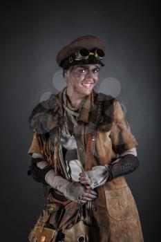 Nuclear post apocalypse life after doomsday concept. Smiling face of grimy female survivor. Studio portrait on black background