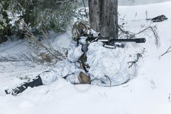 Winter arctic mountains warfare. Action in cold conditions. Sniper with weapons in forest somewhere above the Arctic Circle