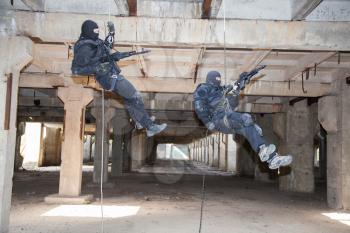 Special forces operators during assault rappeling with weapons 