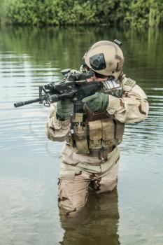 Member of Navy SEAL Team crossing the river with weapons
