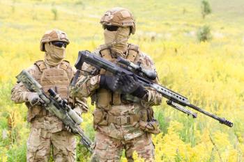 Two equipped and armed soldiers with rifles in the blooming field, team snipers member of ranger squad