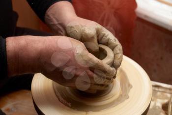 Female hands forming clay pot on the pottery wheel 