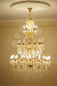 Beautiful crystal ancient chandelier in a hall. Lamp with soft yellow light