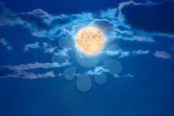 Big shiny moon on the blue sky with clouds