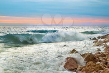 Sea landscape with waves on the beach against sunset
