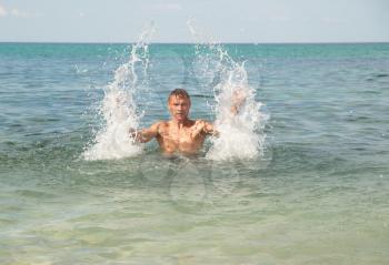 Happy man in the tropical sea with splashes 