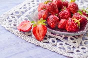 Fresh strawberries in a bowl on wooden table.
