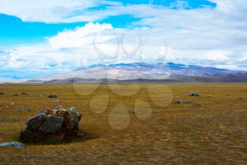 Mountain View steppe landscape, a piece of rock in the foreground, blue sky with clouds. Chuya Steppe,  Kuray steppe in the Siberian Altai Mountains, Russia