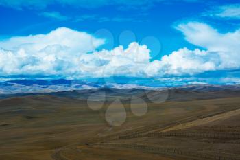 Steppe landscape with a road, mountains, blue sky with clouds. Chuya Steppe  in the Siberian Altai Mountains, Russia