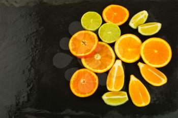 Limes, oranges and lemons on black background, copy space. Fresh food. Ripe fruit. Citrus fruit. Vegetarian food. Fresh fruit. Mixed fruit. Fruit background.