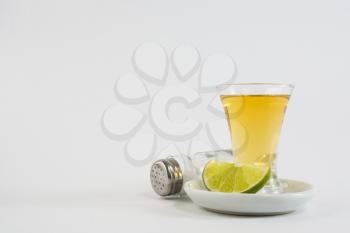Tequila shot with lime and salt on white background. Gold Mexican tequila. Tequila