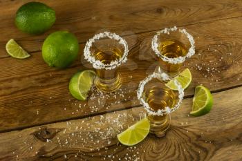 Tequila shots with lime and salt on the wooden background, top view. Tequila.  Gold Mexican tequila. Tequila shot