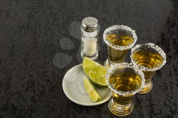 Tequila shots with lime on black background. Alcohol  drink. Gold Mexican tequila. Tequila shot. Tequila. 