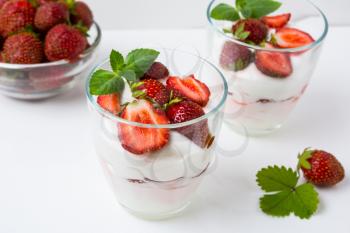 Fresh strawberries dessert layered with yogurt on white background. Diet yogurt dessert with ripe strawberry.