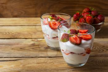 Layered strawberry dessert on wooden background. Diet yogurt dessert with ripe strawberry.