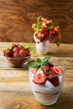 Strawberriy with cream cheese on rustic wooden background. Layered cream dessert with ripe strawberry.