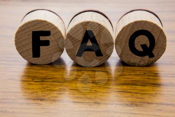 Frequently Asked Questions on the wooden round wheels. Concept of the FAQ word on the wooden background. Web design concept. Caligraphy on the wooden objects.