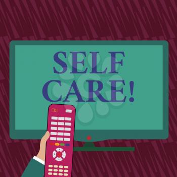 Text sign showing Self Care. Business photo showcasing practice of taking action preserve or improve ones own health Hand Holding Computer Remote Control infront of Blank Wide Color PC Screen