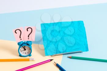 Mini size alarm clock beside stationary placed tilted on pastel backdrop
