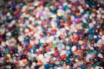 A blurry image of colorful stones. Different kinds of  crystals glittering bright under the shining sun. Beach collectibles and garden beautification accessory
