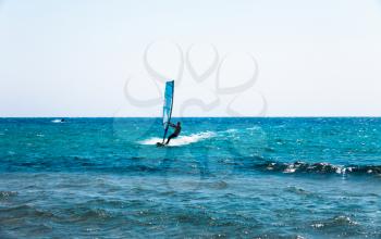 Holiday concept image with the blue sea and the blue sky. Man on the surfing board riding on the waves. Action sports on the water waves. Surfer on the surfing board.