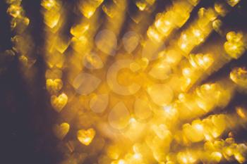 Festive background with defocused golden glitters, bokeh in a shape of a heart.