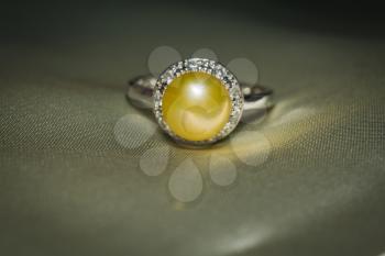 Luxury silver ring with natural freshwater pearl of yellow color, macro.