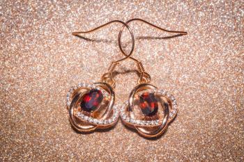 Fashion golden earrings with a dark red garnet stone.