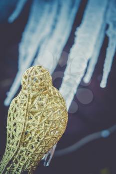 Decorative element artificial glittering golden bird, ornamental Christmas toy, filtered background.