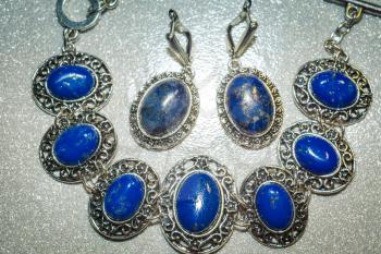Vintage silver earrings and bracelet with natural stone, blue lapis lazuli background.