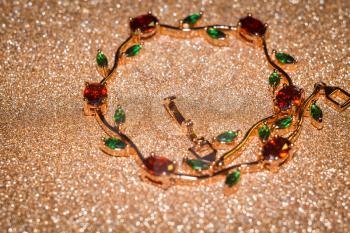Decorative rose gold bracelet with ruby red and green zircons, floral themed jewellery.