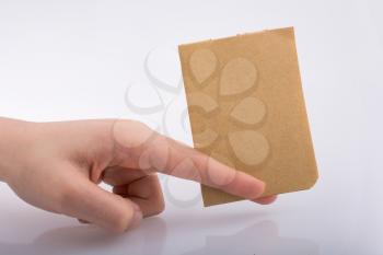 Hand holding a brown color sheet of paper on a white background