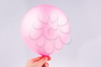 Hand holding a pink balloon on a white background