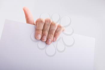 Hand holding a white sheet of paper on a white background