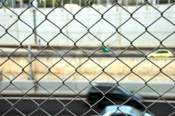 Speeding cars on the motorway seen through wire mesh fence. Motion blur.