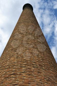 Weathered industrial brick chimney of an abandoned factory.