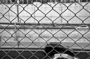Speeding blurred cars on the motorway and wire mesh fence. Black and white.