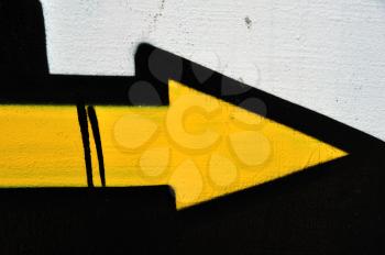 Yellow arrow graffiti sprayed on wall. Abstract background texture.