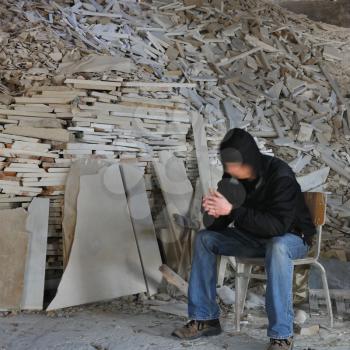 Motion blurred man sitting next to a pile of marble fragments in abandoned interior.